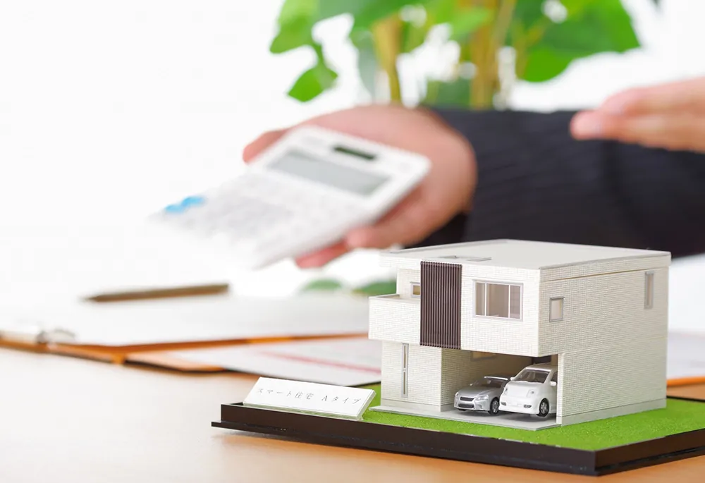 住宅模型と電卓を使って不動産契約を丁寧にご案内する様子